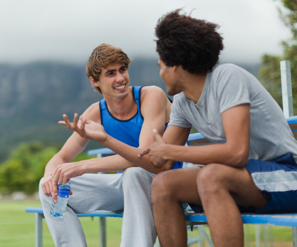 two teens enjoying conversation on a bench