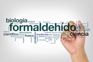 a hand with a pen writing a word cloud featuring formaldehyde as the largest term